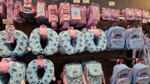 Stitch merchandise display at Walkden Town Centre Home Bargains, featuring neck pillows, backpacks, lanyards, passport holders, and accessories in a themed blue and pink colour scheme.