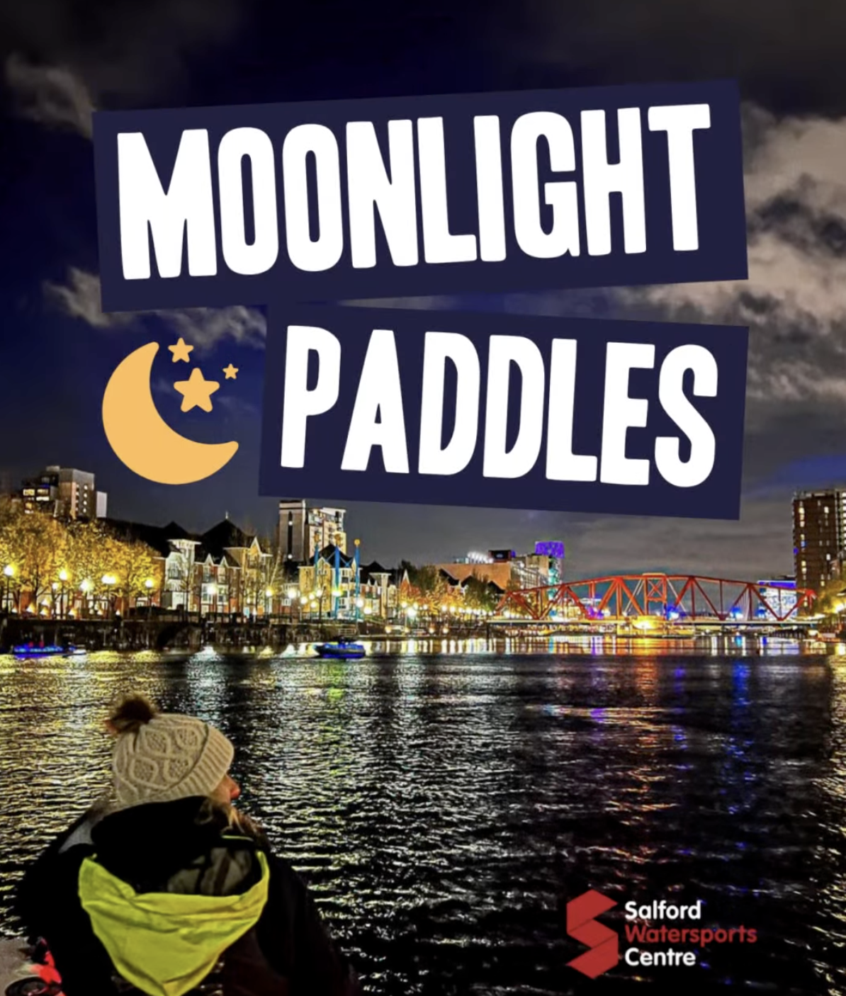 Person kayaking at night on Salford Quays during a Moonlight Paddle session, with city lights reflecting on the water and Salford Watersports Centre branding.